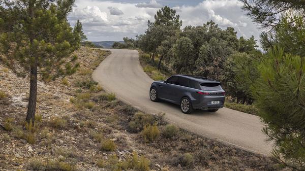 Blue Range Rover Sport from behind driving up a hill